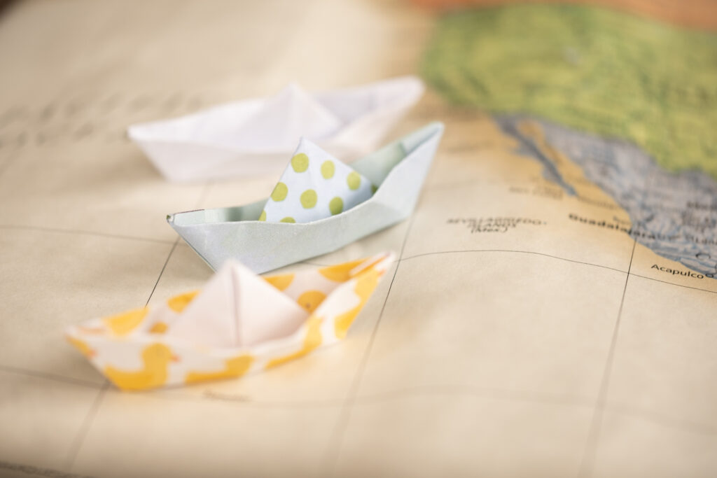 paper boats sailing in the Pacific Ocean off the west coast of North America on a paper map.
