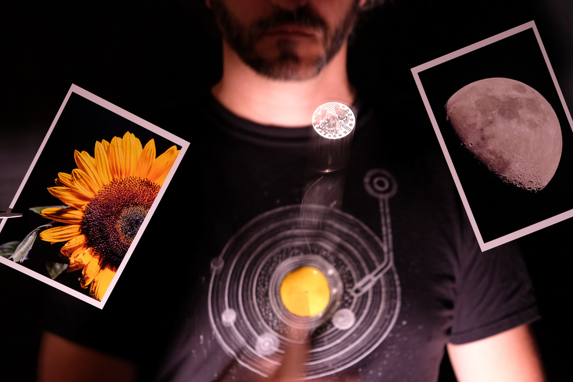 Man wearing tshirt with solar system, holding photos of sunflower and moon, photography by Maayan Windmuller