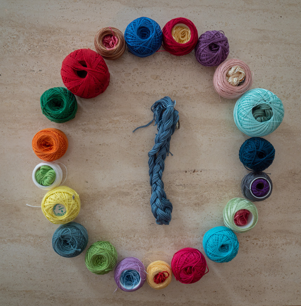 20 colorful spools of thread with one skein in the middle